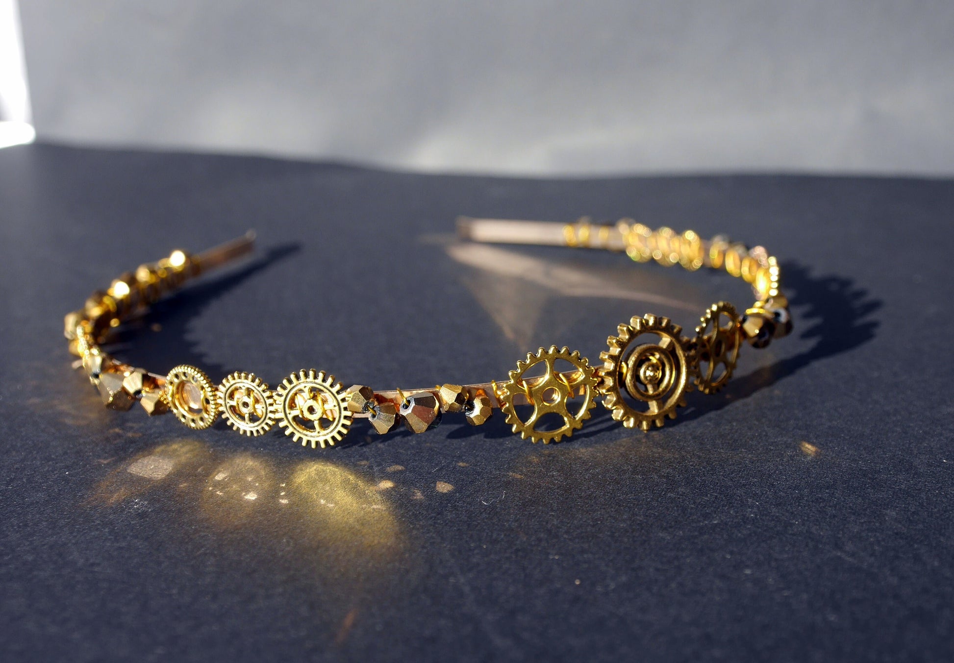 A silver toned or gold tiara band (4 mm width approx) with a cog and gear embellishments (between 1 cm - 2 cm approx in size) hand wound with silver toned or gold wire and gold/silver glass beads (4 mm and 6 mm).